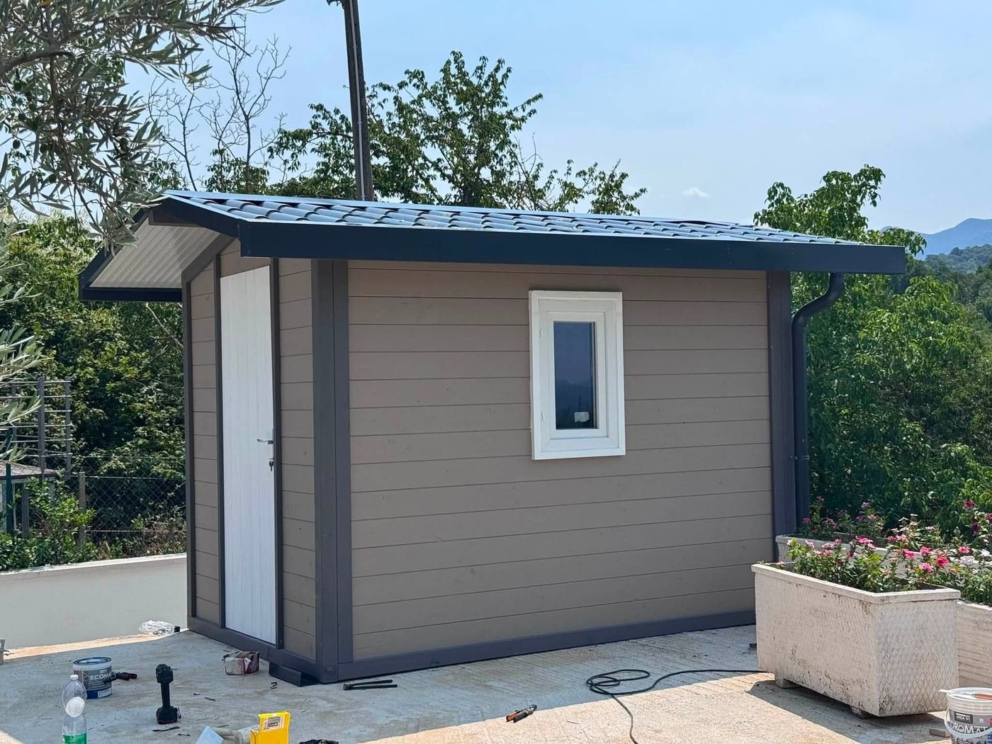 Casetta in legno rivestita in grigio antracite con infissi in PVC e grondaia, installata su un terrazzo